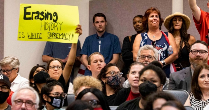 Person holds sign that says "Erasing history is white supremacy"