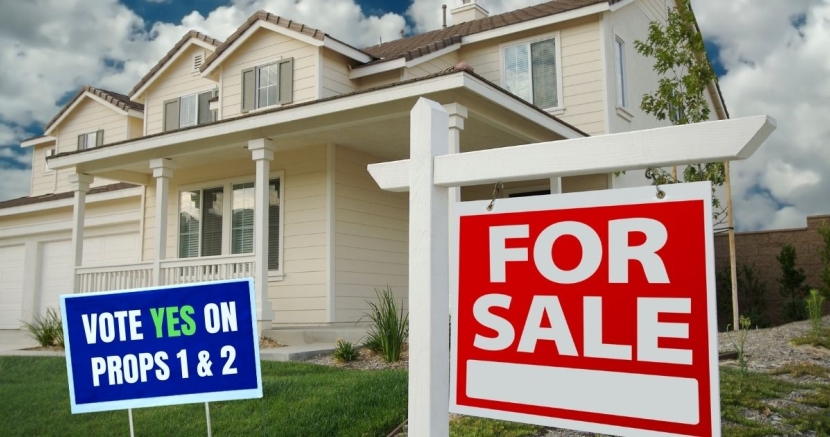 Home with a for sale sign and sign saying to vote YES on Props 1 and 2