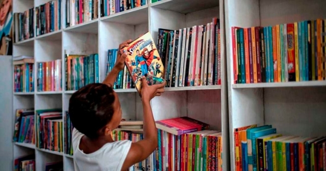 Student removing book from shelf. 